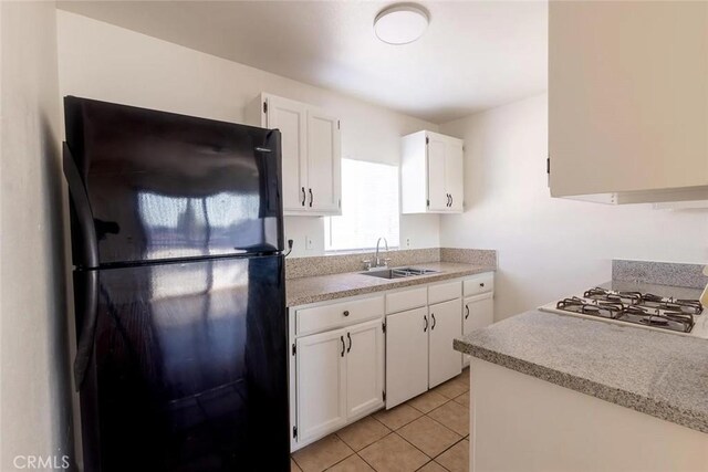 kitchen featuring stainless steel gas cooktop, white cabinetry, black refrigerator, and sink