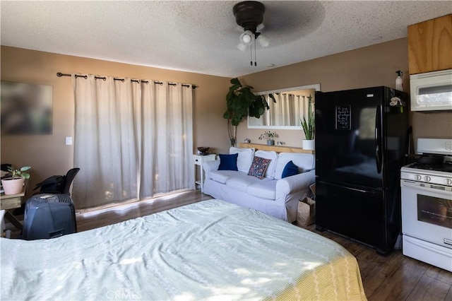 bedroom with ceiling fan, dark hardwood / wood-style floors, black fridge, and a textured ceiling