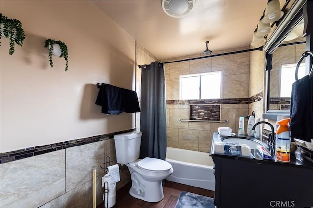 full bathroom featuring shower / tub combo, hardwood / wood-style floors, toilet, vanity, and tile walls