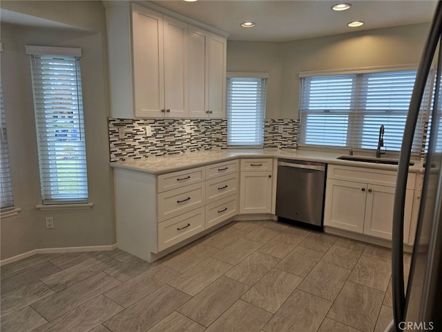 kitchen featuring dishwasher, white cabinets, tasteful backsplash, and sink