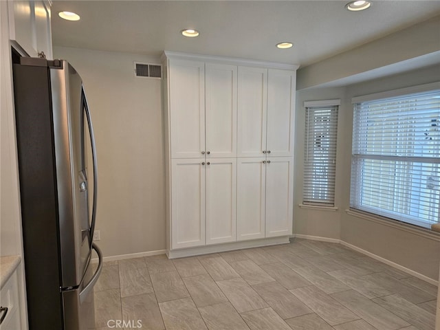 kitchen featuring stainless steel refrigerator and white cabinetry