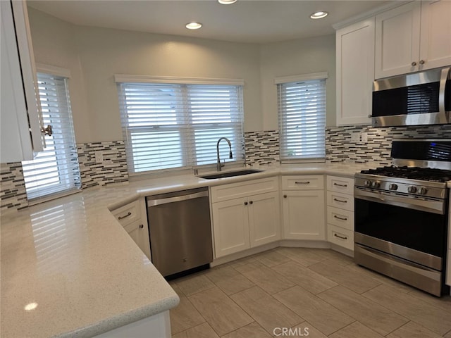 kitchen with stainless steel appliances, white cabinetry, a healthy amount of sunlight, and sink