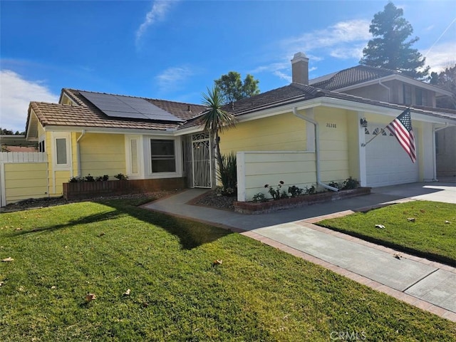 ranch-style home with solar panels, a garage, and a front yard