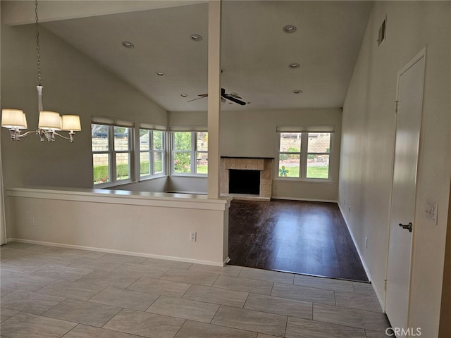 unfurnished living room featuring high vaulted ceiling, light hardwood / wood-style floors, and ceiling fan with notable chandelier