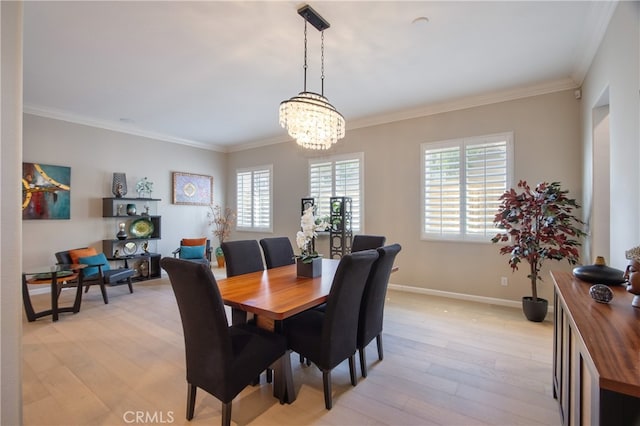 dining area with crown molding, an inviting chandelier, and light wood-type flooring