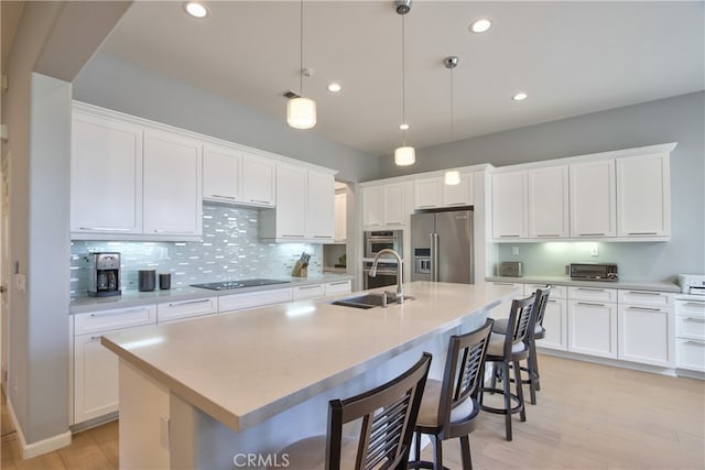 kitchen featuring white cabinets, high end refrigerator, decorative light fixtures, and a kitchen island with sink