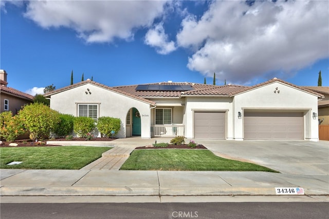 mediterranean / spanish house featuring a garage, a front yard, and solar panels