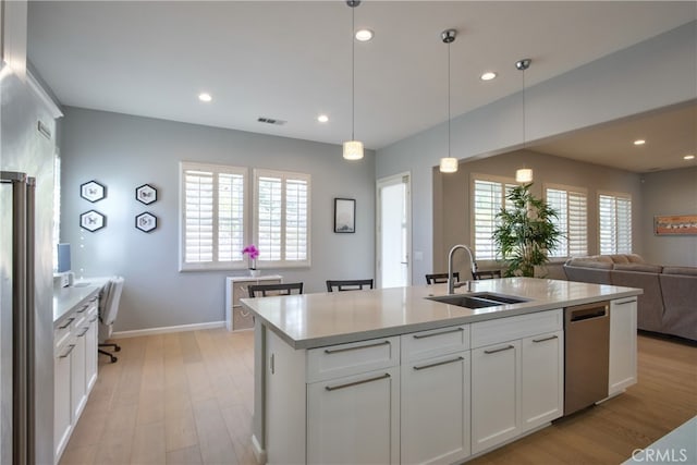 kitchen with a wealth of natural light, white cabinetry, sink, and light hardwood / wood-style floors