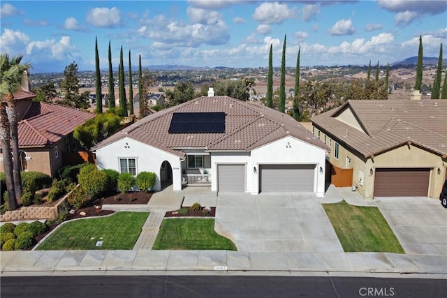 mediterranean / spanish home with a garage, a front yard, and solar panels