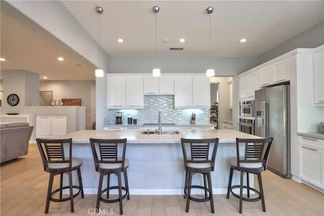 kitchen with sink, high end refrigerator, light hardwood / wood-style flooring, pendant lighting, and white cabinets