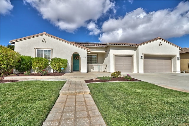 mediterranean / spanish-style home featuring solar panels, a front lawn, covered porch, and a garage