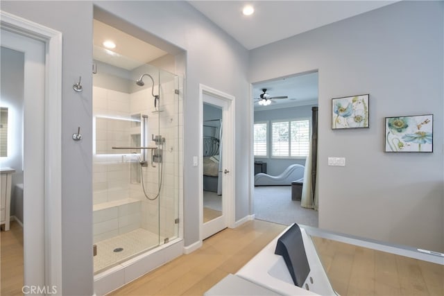 bathroom featuring wood-type flooring, a shower with door, and ceiling fan