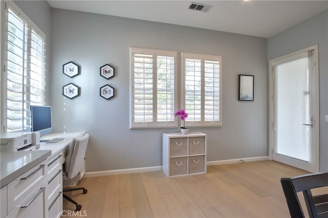 office with light hardwood / wood-style floors and a healthy amount of sunlight