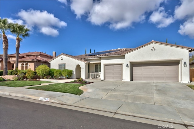 mediterranean / spanish-style home with solar panels, a garage, and a front yard