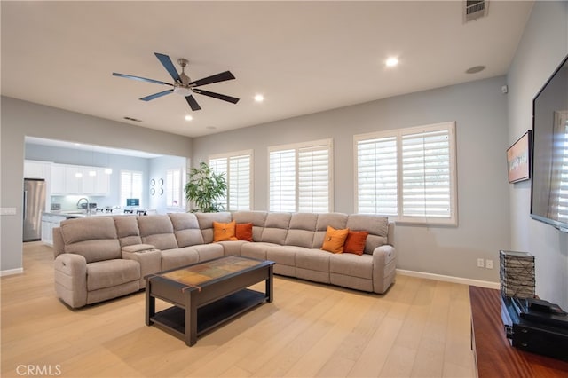 living room featuring a wealth of natural light, light hardwood / wood-style flooring, ceiling fan, and sink