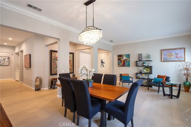 dining space with light hardwood / wood-style floors, crown molding, and a chandelier