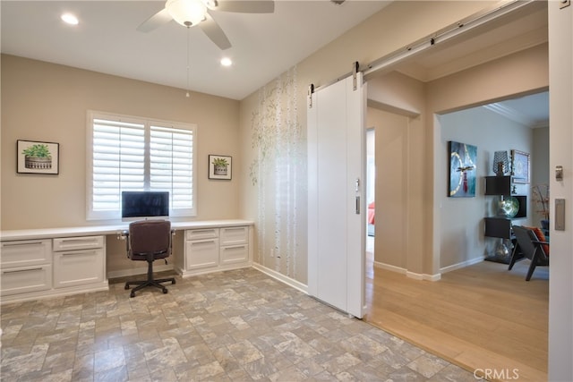 office area featuring ceiling fan, crown molding, a barn door, built in desk, and light hardwood / wood-style flooring