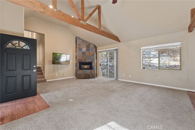 unfurnished living room featuring a tile fireplace, carpet, high vaulted ceiling, and beam ceiling