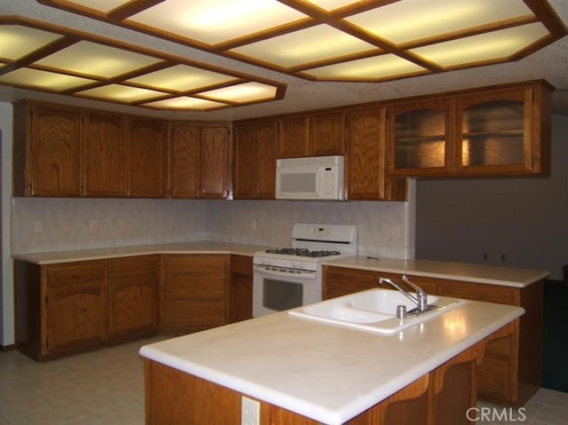 kitchen featuring backsplash, white appliances, and sink