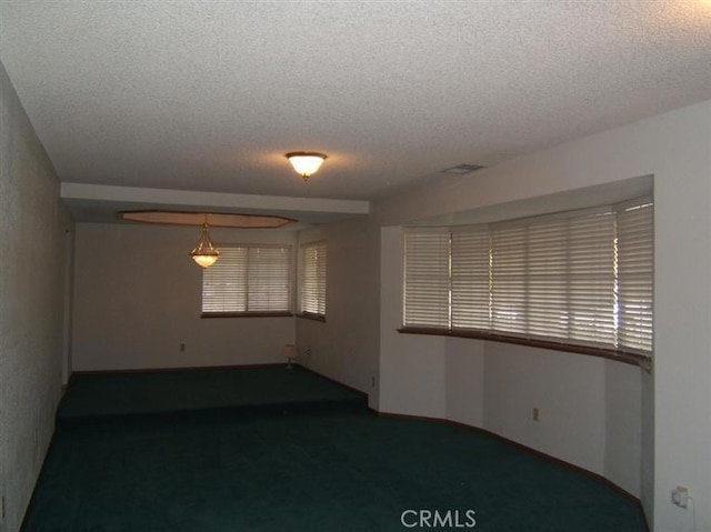 carpeted spare room with a textured ceiling