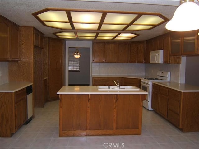 kitchen with backsplash, sink, an island with sink, and white appliances