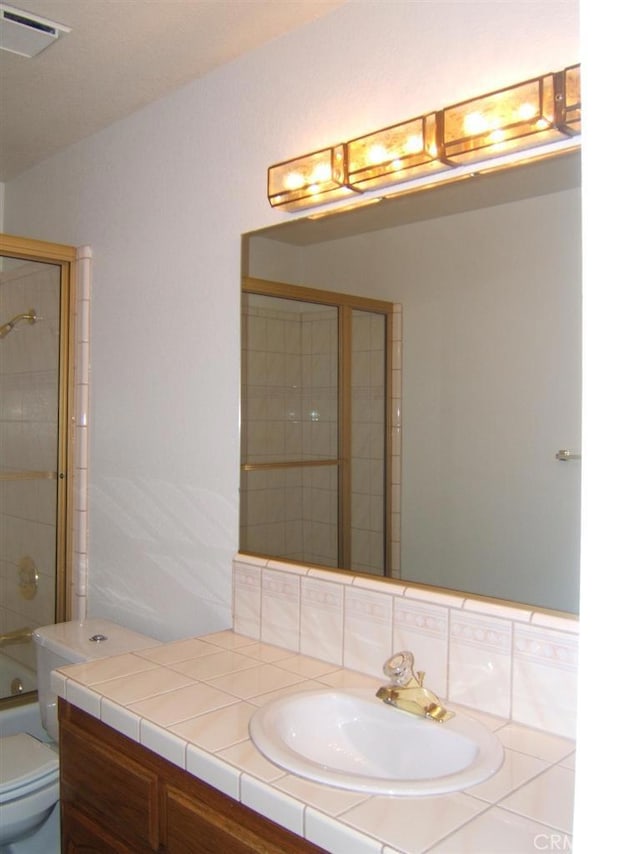 full bathroom featuring shower / bath combination with glass door, vanity, tasteful backsplash, and toilet