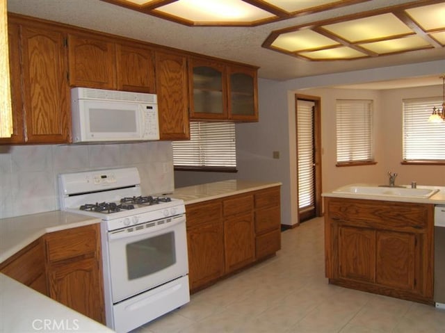 kitchen featuring decorative light fixtures, decorative backsplash, white appliances, and sink