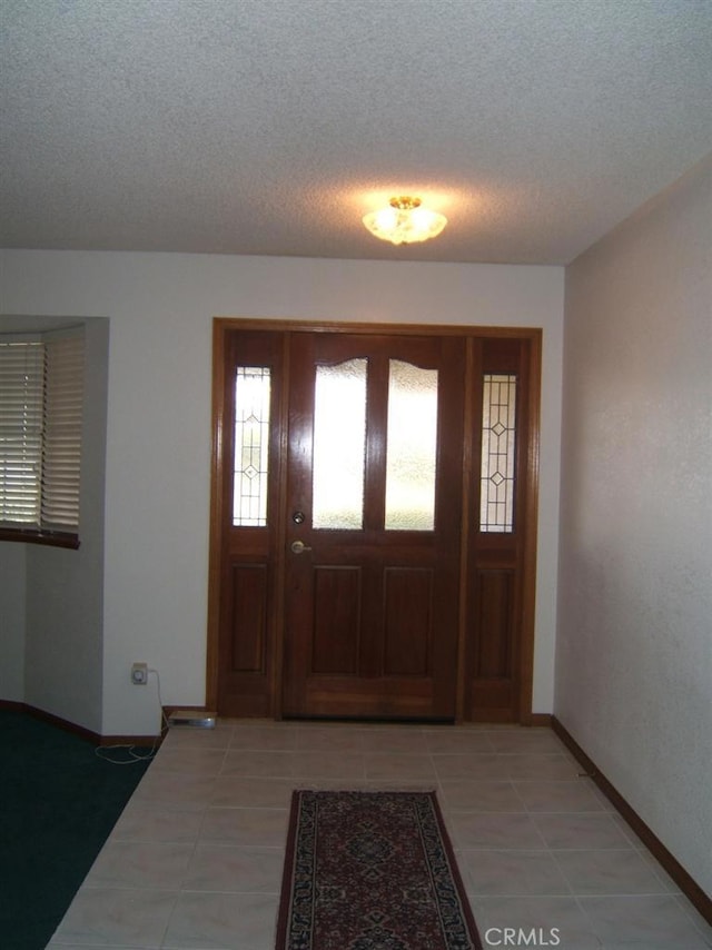 foyer featuring light tile patterned floors and a textured ceiling