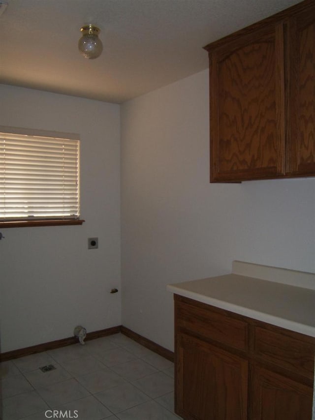 washroom featuring electric dryer hookup, light tile patterned floors, and cabinets