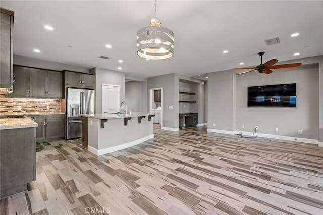 kitchen with stainless steel refrigerator with ice dispenser, ceiling fan with notable chandelier, decorative light fixtures, and light hardwood / wood-style flooring