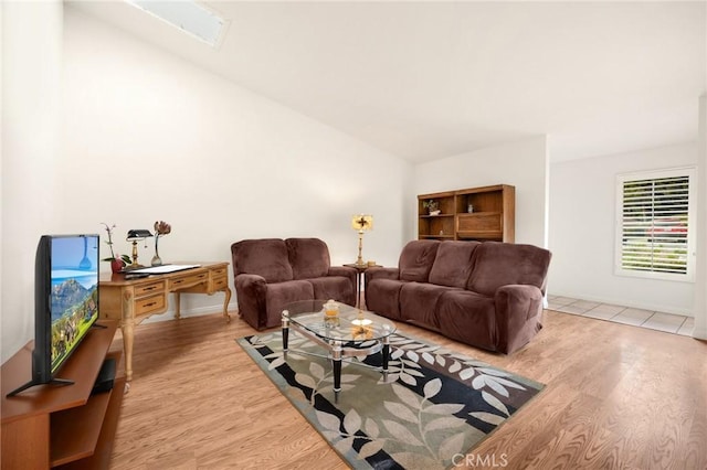 living room with light hardwood / wood-style flooring and lofted ceiling with skylight