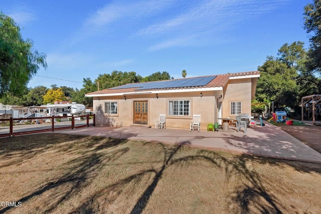 back of house with a lawn, a patio area, and solar panels