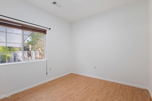 unfurnished room with light wood-type flooring, visible vents, and baseboards