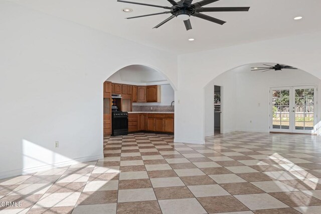 kitchen featuring ceiling fan, open floor plan, light countertops, french doors, and black gas range oven