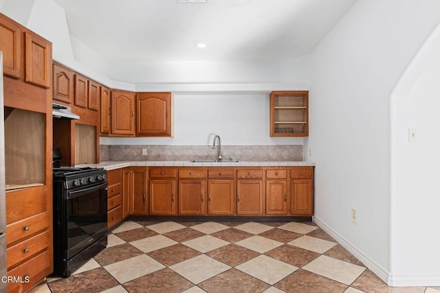 kitchen with black gas range, decorative backsplash, brown cabinetry, under cabinet range hood, and a sink