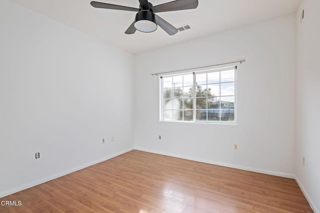 empty room with light wood-style floors, visible vents, baseboards, and a ceiling fan