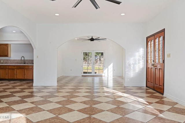 unfurnished living room featuring arched walkways, ceiling fan, french doors, a sink, and recessed lighting