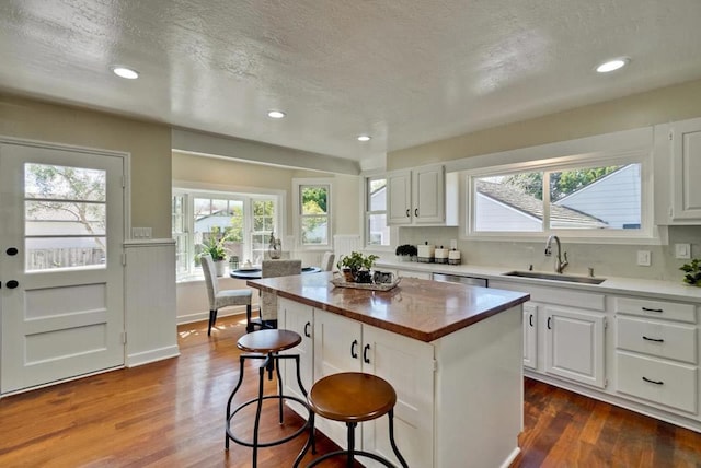 kitchen with a kitchen breakfast bar, sink, a kitchen island, and white cabinets