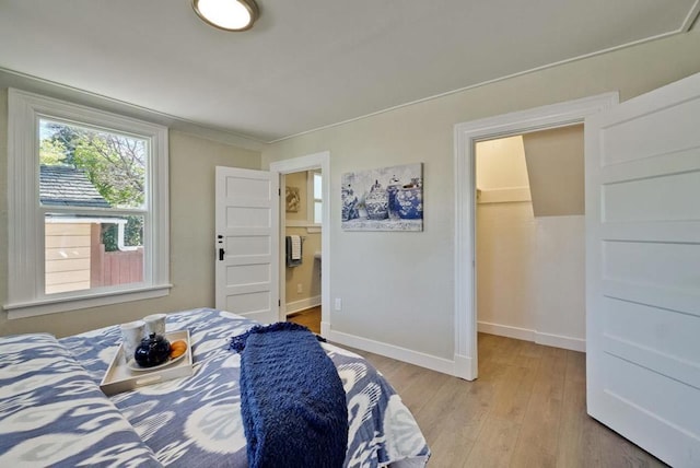 bedroom with a spacious closet and light wood-type flooring