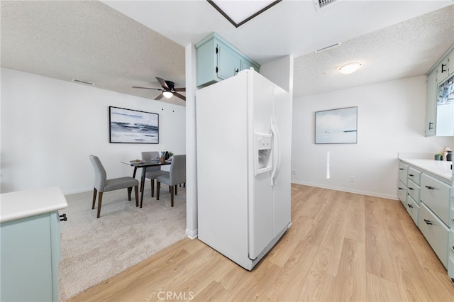 kitchen featuring a textured ceiling, white fridge with ice dispenser, ceiling fan, and light hardwood / wood-style flooring