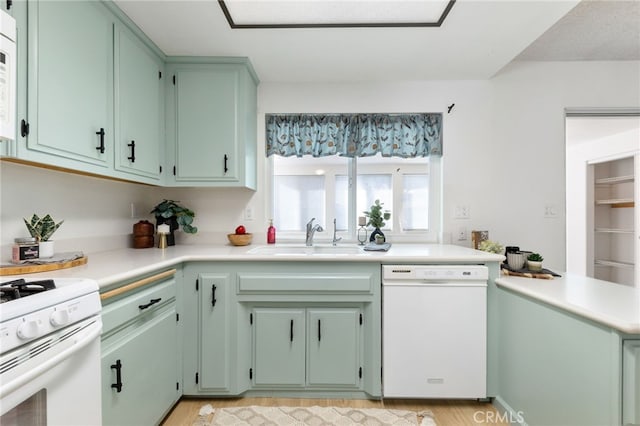 kitchen with sink, white appliances, kitchen peninsula, and light hardwood / wood-style floors