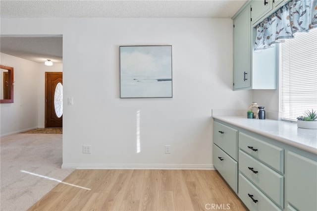 kitchen featuring a textured ceiling, green cabinetry, and light hardwood / wood-style flooring