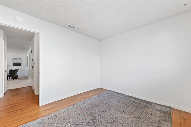 unfurnished room featuring hardwood / wood-style flooring and a textured ceiling