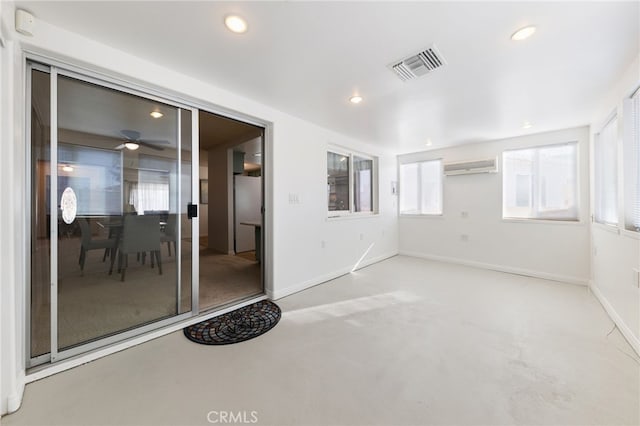 empty room featuring a wall mounted air conditioner and ceiling fan