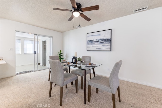 carpeted dining room with ceiling fan and a textured ceiling