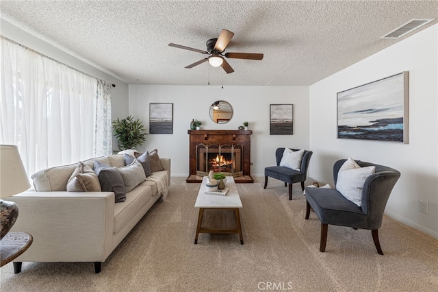 living room featuring a fireplace, light carpet, a textured ceiling, and ceiling fan