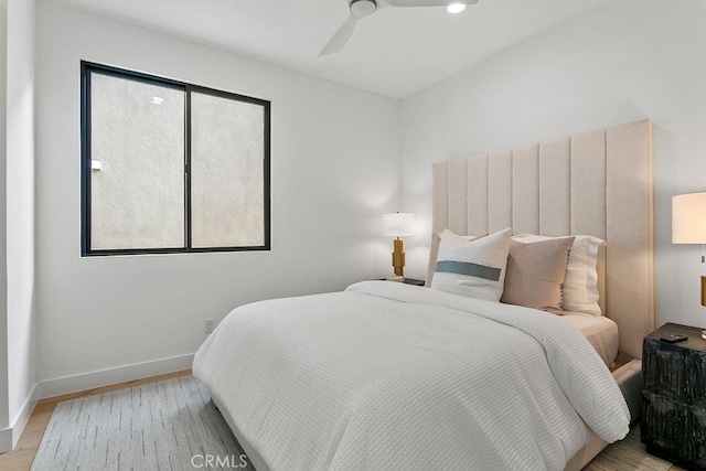 bedroom featuring baseboards, light wood-style floors, and a ceiling fan