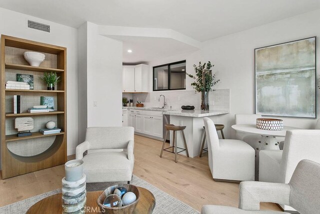 living area with recessed lighting, visible vents, and light wood-style flooring