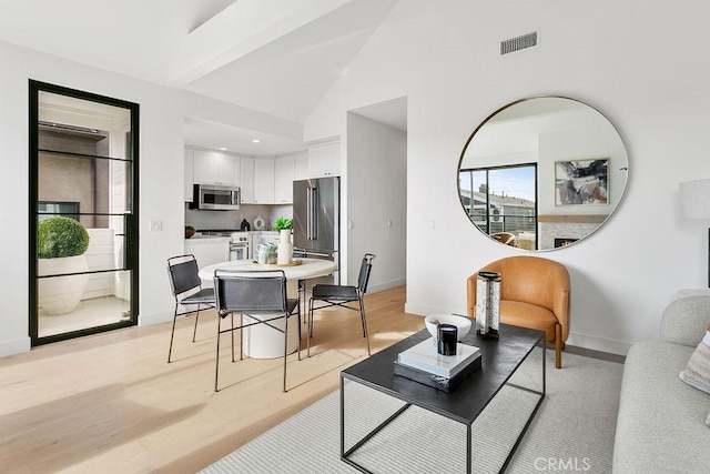 living room featuring visible vents, baseboards, and light wood-style floors