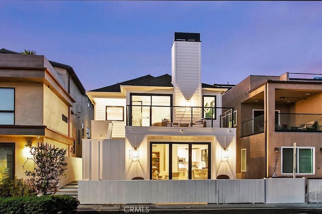 back house at dusk featuring a balcony